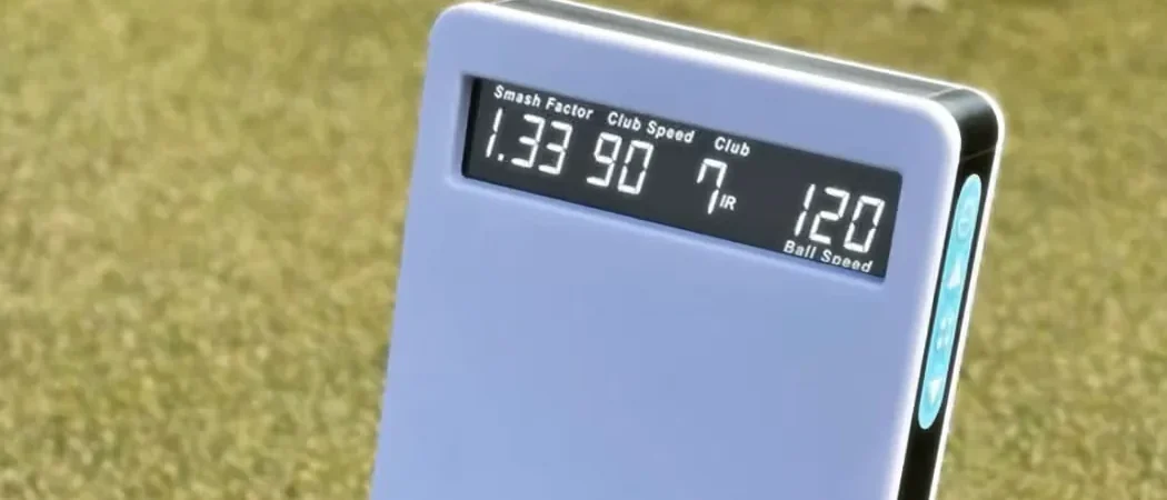 ESB1 launch monitor on the turf, its readout showing smash factor 1.33, club speed 90, a 7 iron and ball speed 120